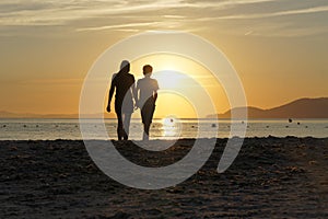 Mother and son admire together the sunset at the sea. Holiday at the beach