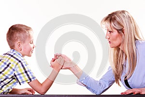 Mother and son arm wrestle sit at table.