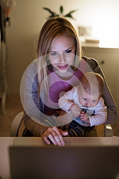 Mother with son in the arms, working on laptop