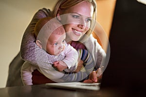 Mother with son in the arms, working on laptop