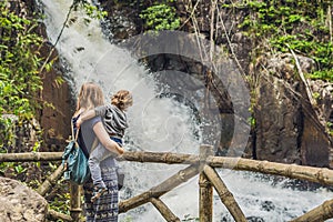 Mother and son in the background of beautiful cascading Datanla waterfall In the mountain town Dalat, Vietnam