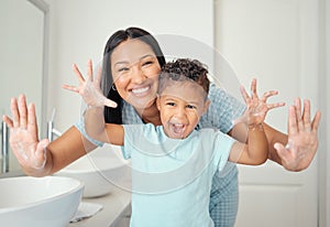 Mother and son in bathroom with clean hands, open palms that are cleaned and covered in foam teaching child hand washing