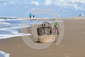 Mother and son on the beach in the distance and picnic basket