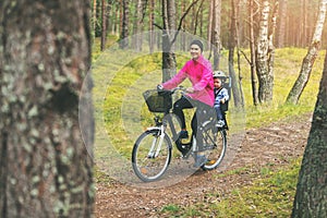 Mother with son in bike child seat cycling on forest trail