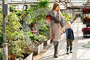 Mother and son bought a plant and are walking in the garden center.