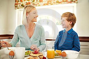 Mother, son and breakfast in house kitchen for eating, pancakes and nutrition with plate, knife and fork. Woman, kid and