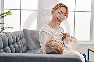 Mother and son breastfeeding kid sitting on sofa at home