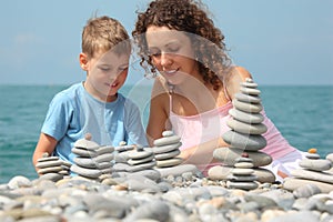 Mother and son builds stone stacks on beach