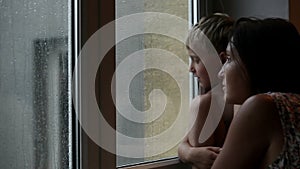 Mother and son conversation on the windowsill during autumn rainy day