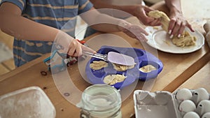 Mother and son cook child and woman put dough into dish