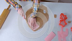 Mother and son are cutting parts for gingerbread house from dough hands closeup.