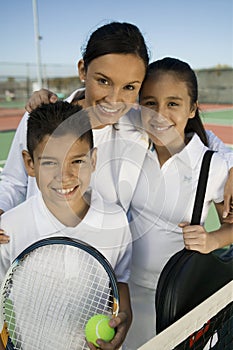 Mother with son and daughter by net on tennis court portrait