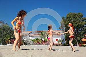 Mother with son and daughter plays on beach