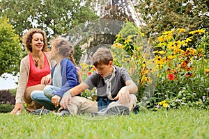 Mother, son and daughter sitting on the grass in
