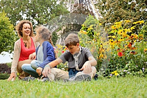 Mother, son and daughter sitting on grass in