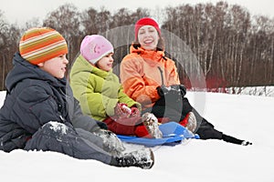 Mother, son and daughter sitting on snow