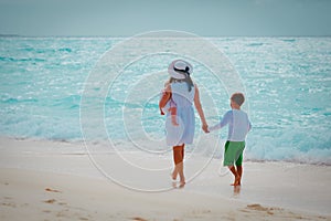 Mother with son and daughter walking on beach at sunset