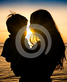 Mother and son in a deep moment of love during sunset at beach