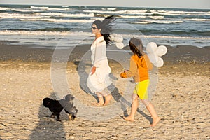 Mother ,son and dog running on the beach