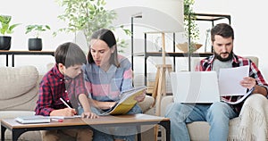 Mother with son doing homework while father is working from home