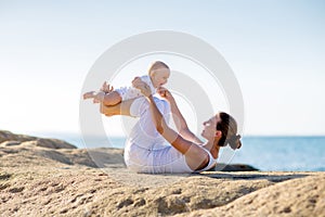 A mother and a son are doing yoga exercises at the seashore of M