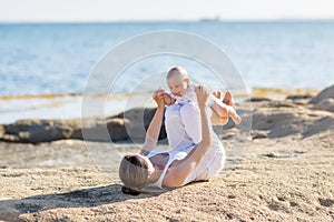 A mother and a son are doing yoga exercises at the seashore of M