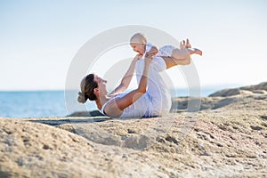 A mother and a son are doing yoga exercises at the seashore of M