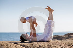 A mother and a son are doing yoga exercises at the seashore of M