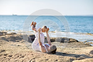 A mother and a son are doing yoga exercises at the seashore of M