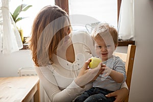 Mother and son eating an apple at the kitchen