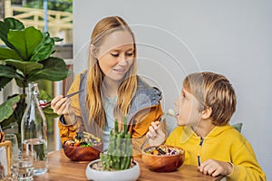 Mother and son eating Raw Organic Poke Bowl with Rice and Veggies close-up on the table. Top view from above horizontal