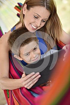 Mother and son enjoying in hammock using tablet