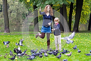 Mother and son feeding pigeons in a park