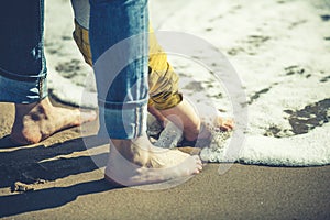 Mother and son with feet in the shore water. Love and protection.