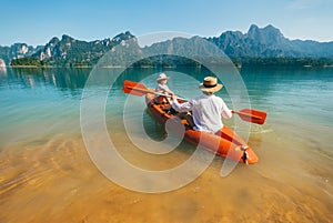 Mother and son floating on kayak together on Cheow Lan lake in Thailand