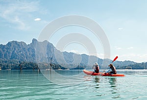 Mother and son floating on kayak together on Cheow Lan lake in Thailand