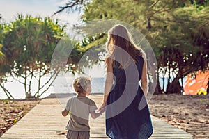 Mother and son go to the sea beach. Resort vacation on tropical beach. Path to beach