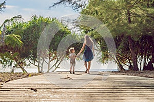 Mother and son go to the sea beach. Resort vacation on tropical beach. Path to beach