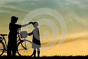 Mother and son having fun riding bike at sunset,Silhouette a kid at the sunset,