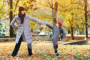 Mother and son having fun together in autumn park. Happy family on walk. Autumn vacations
