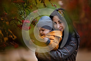 Mother and son having fun together in autumn park. Happy family walking in yellow trees in fall. Thanksgiving holiday