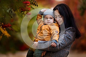 Mother and son having fun together in autumn park. Happy family walking in yellow trees in fall. Thanksgiving holiday