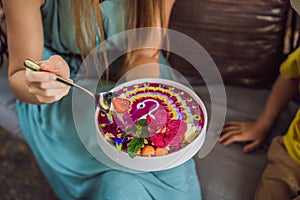 Mother and son having a mediterranean breakfast seated at the sofa and eats Healthy tropical breakfast, smoothie bowl