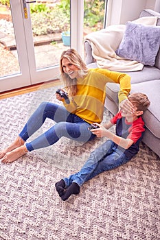 Mother And Son At Home Playing Video Game Together With Woman Cheating To Win