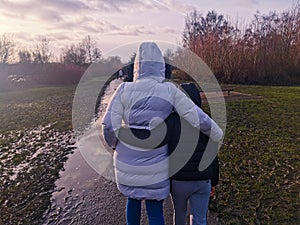 Mother and son hug as they walk in a park on a cold rainy day