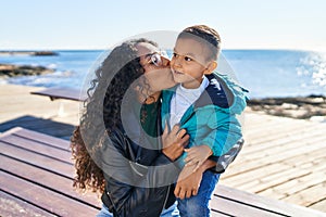 Mother and son hugging each other and kissing sitting on bench at seaside