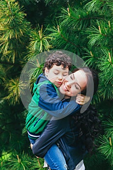 Mother and son hugging each other, playing in the park in spring sunny day, Happy family life