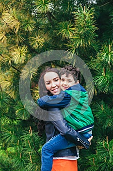 Mother and son hugging each other, playing in the park in spring sunny day, Happy family life