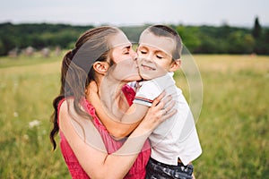 Mother and son hugging in field. Happy mother embracing her son in park. Mother hugging her child. Motherhood. Young mother cuddle