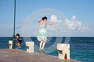 Mother and son jumping into the ocean